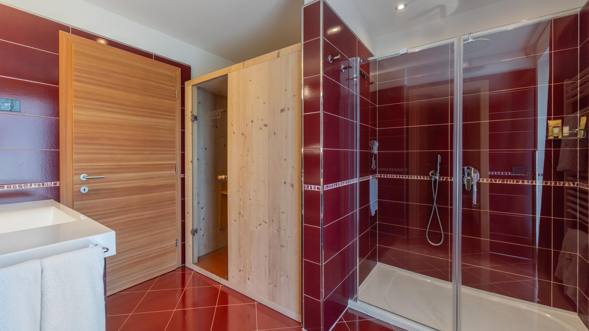 Bagno moderno con sauna e doccia, piastrelle rosse.