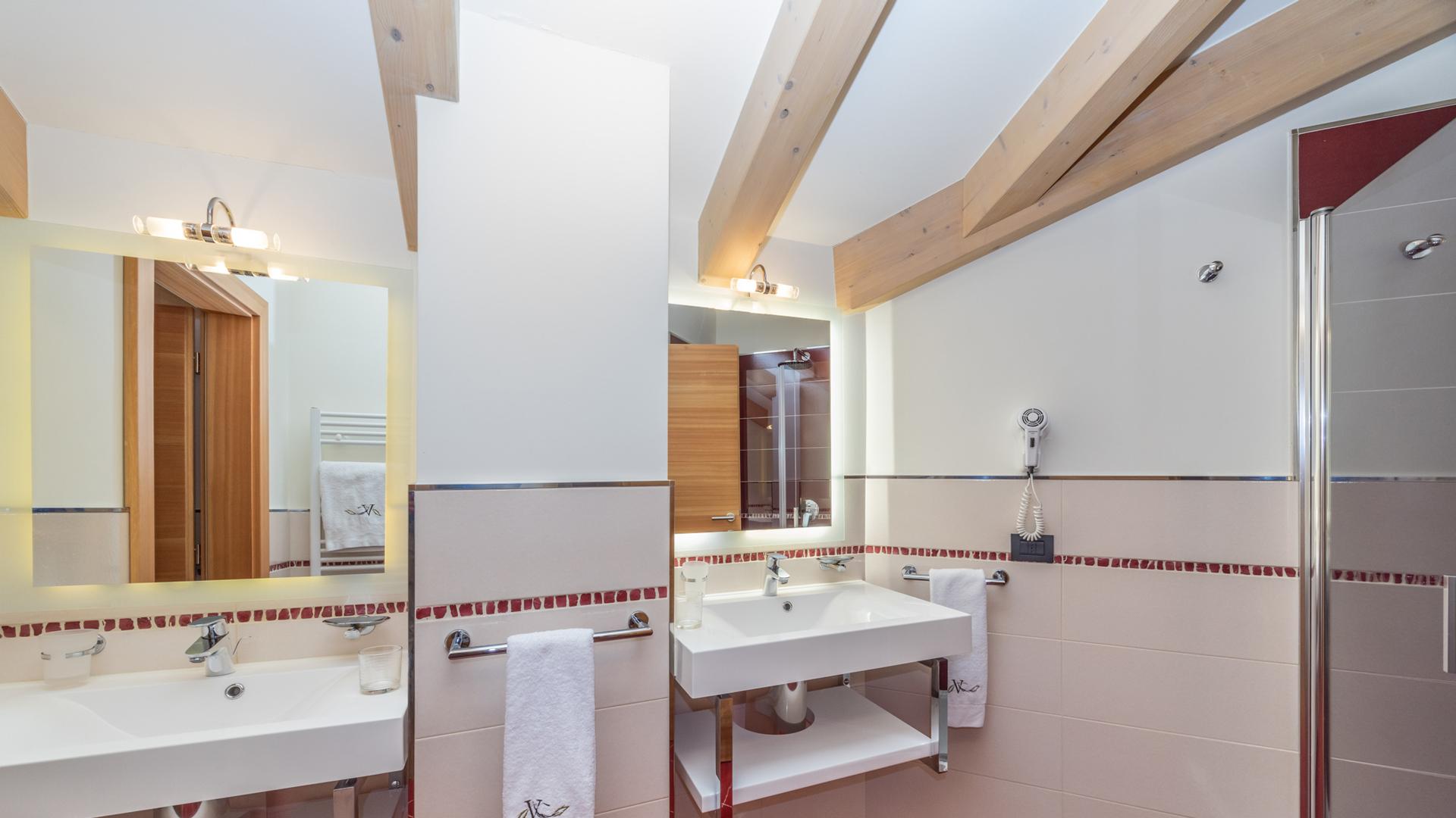 Bagno moderno con lavandini doppi e piastrelle rosse.