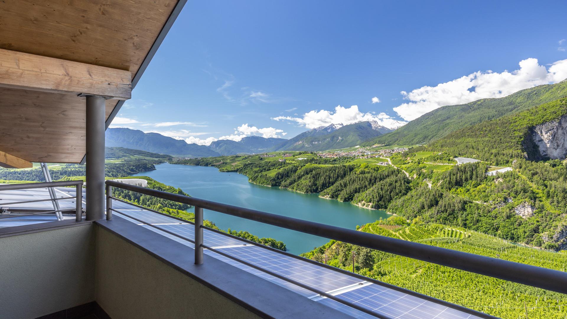 Panoramablick auf einen See und Berge von einem Balkon.