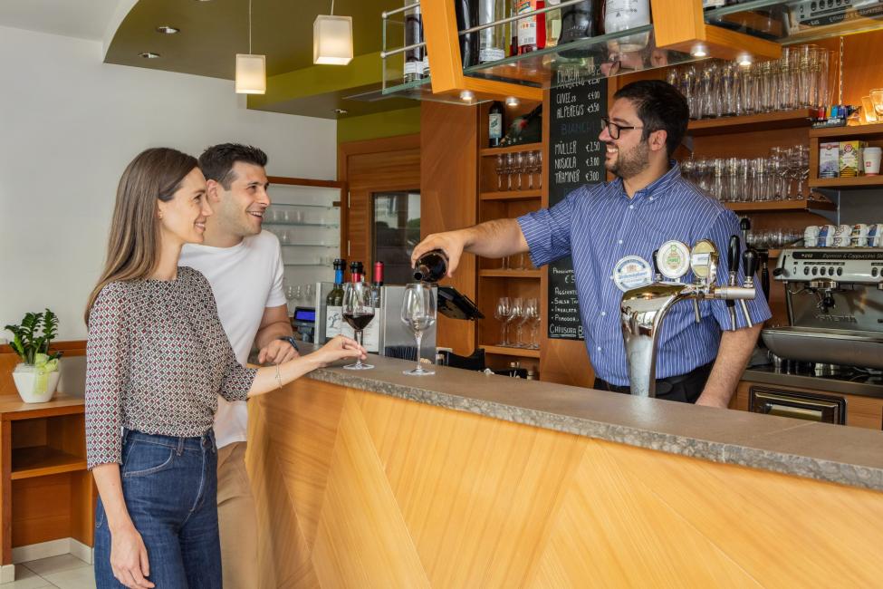 Coppia al bar riceve vino dal barista sorridente.