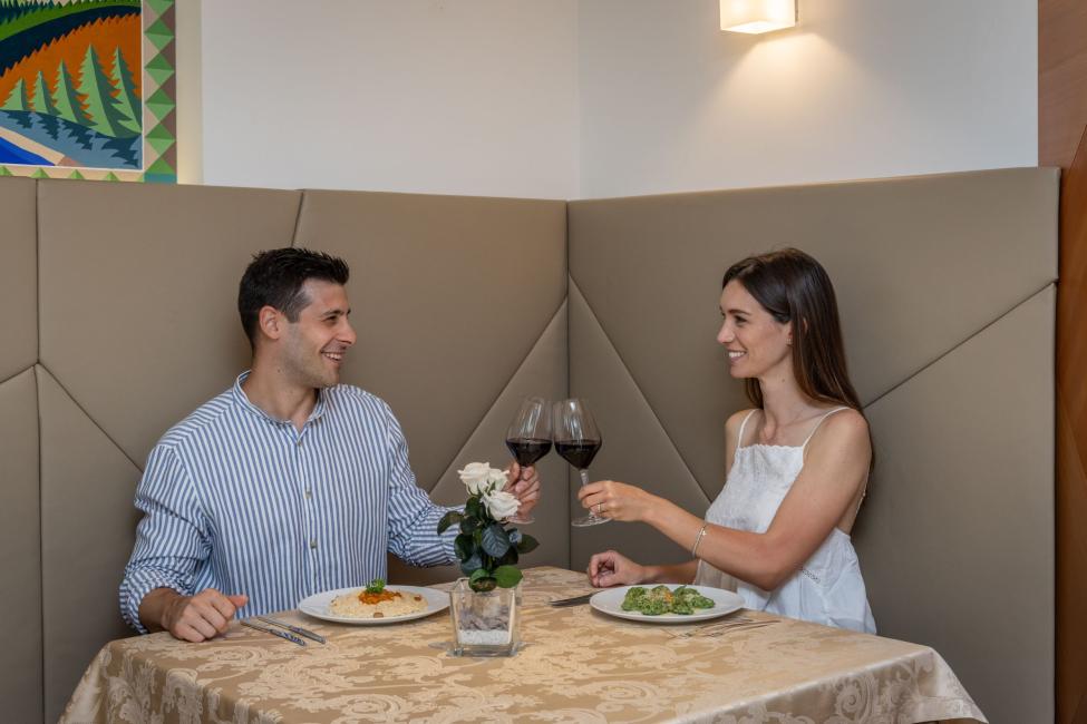 Coppia brinda con vino rosso in un ristorante elegante.